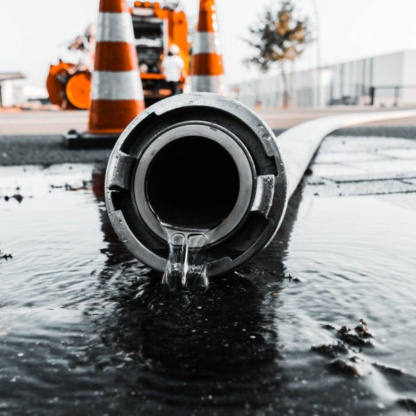 Selective closeup shot of a gray pipe with water coming out its hole
